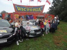 grupa-usmiechnietch-dzieci-i-wychowawcow-pozuje-w-tle-widac-namiot-cyrkowy-oraz-taksowki-firmy-tele-taxi.jpg