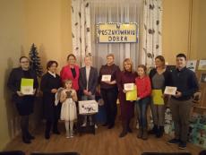 Grupa zaproszonych gości pozuje do zdjęcia pokazując dyplomy i medale