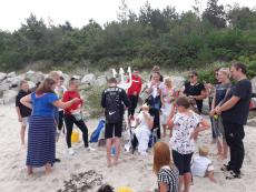 Neptunalia - chłopiec przebrany za Neptuna siedzi na tronie - leżaku. Za nim stoi grupa wychowawców przed nim dzieci czekające na pasowanie na kolonistów. 